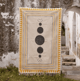Decorative tapestry with geometric design hanging on a stone wall.