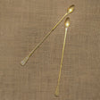 Two gold spoons on a textured brown fabric background