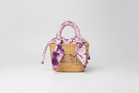 Woven basket with a purple and white tie-dye cover on a white background