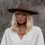 Woman wearing a wide-brimmed hat and light-colored shirt in a natural setting