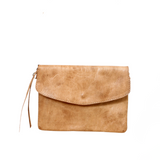 Brown leather crossbody bag on a white background with a plant leaf in the corner