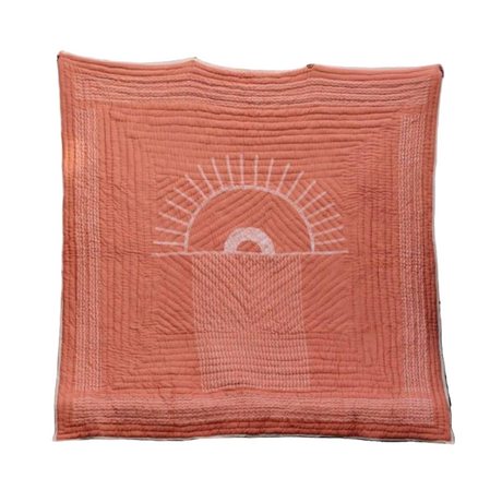 Coral-colored quilt with a sun design on a white background