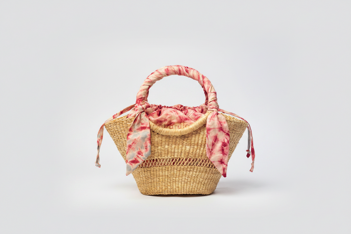 Woven handbag with a pink floral scarf on a light gray background