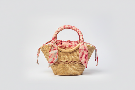 Woven handbag with a pink floral scarf on a light gray background