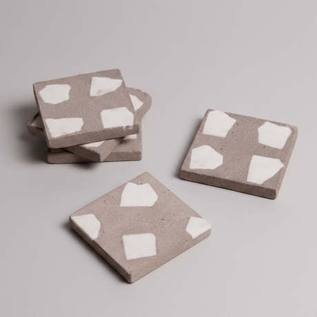 Three square coasters with white heart patterns on a light gray background