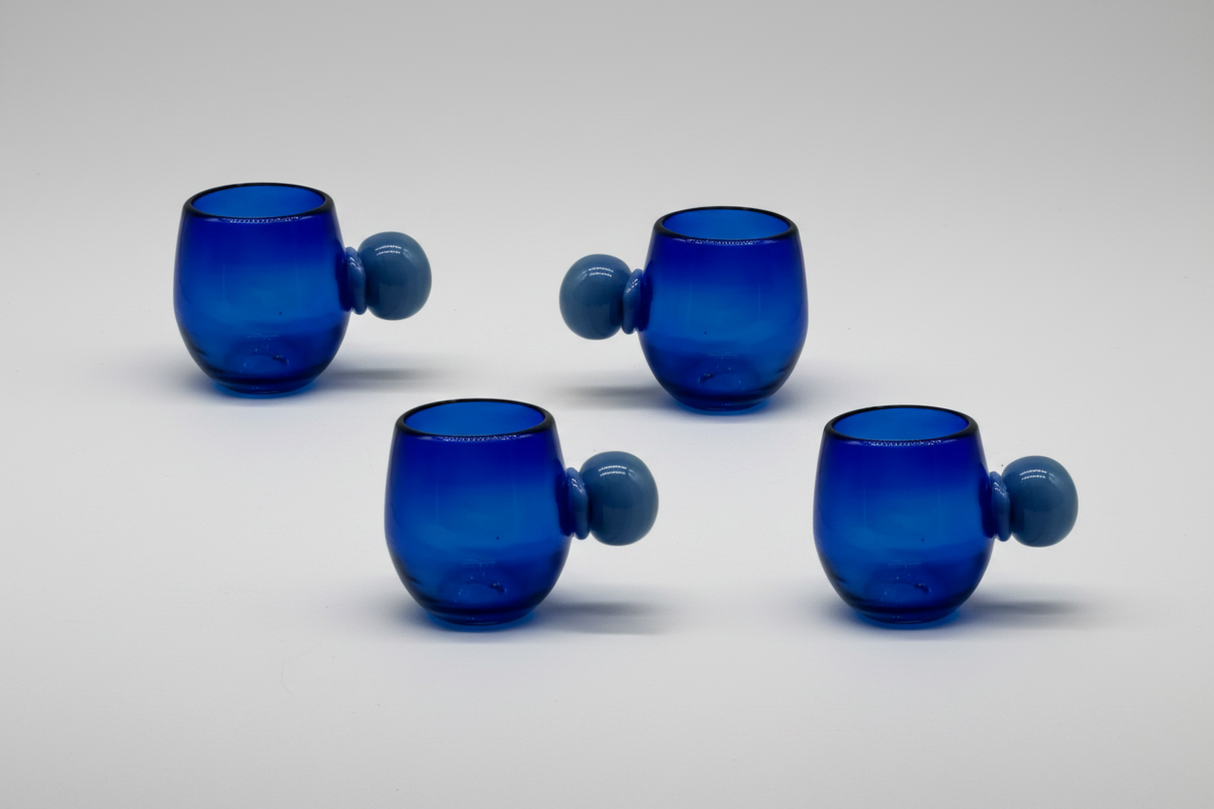 Four blue glass tumblers with spherical handles on a light gray background