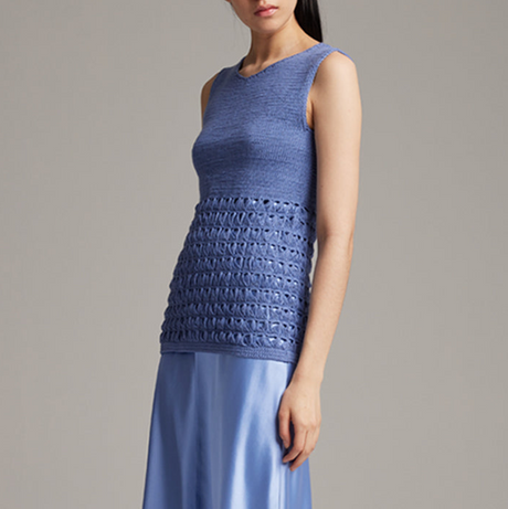 Woman wearing a blue sleeveless top with a textured pattern on a gray background