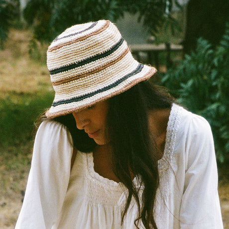 Woman wearing a striped hat and white dress outdoors