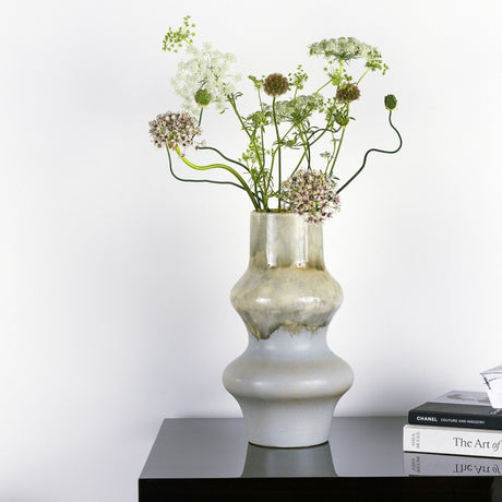 Decorative vase with flowers on a black surface against a white background