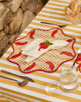 Outdoor setting with a striped tablecloth, plates, cutlery, and snacks on a stone wall background.