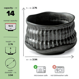 The Black Ceramic Meisen Matcha Bowl, a Minoyaki pottery piece, has a ribbed texture and holds 14 oz. It measures 2.76" high and 3.94" wide, is microwave safe but not dishwasher safe—ideal for traditional tea rituals.