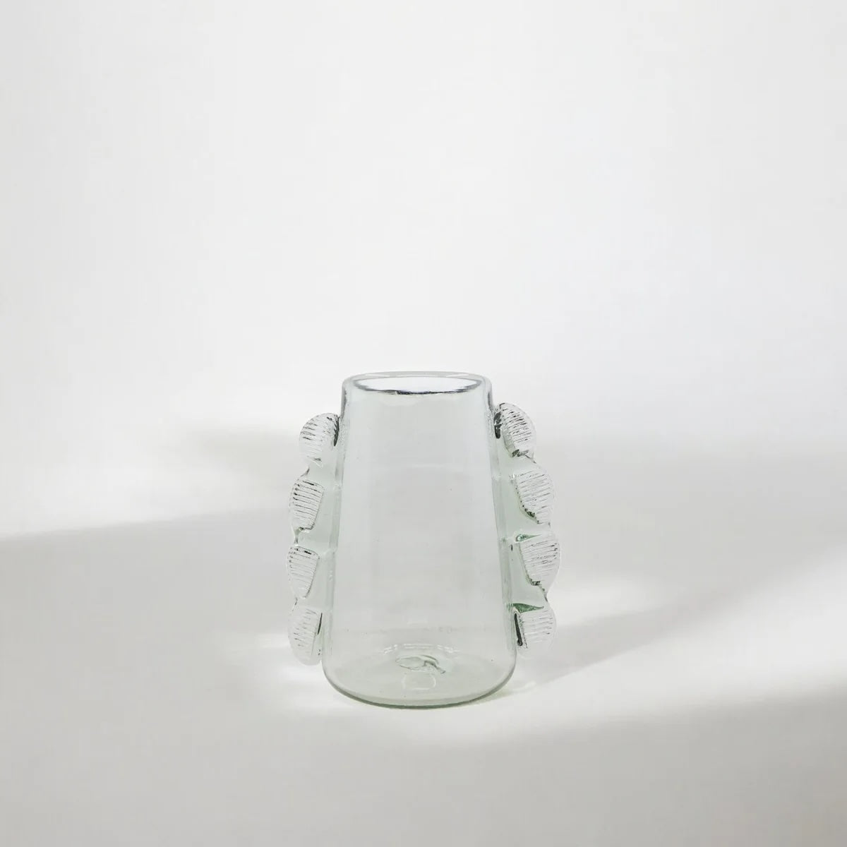 Clear glass vase with decorative tassels on a white background