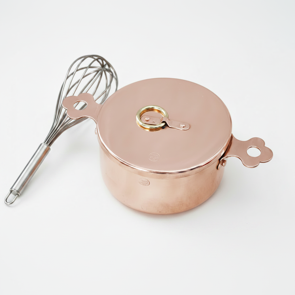 Copper pot with lid and whisk on a white background