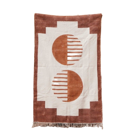Rug with geometric pattern draped over a chair against a warm-toned wall.