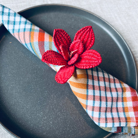 Plaid napkin with a red floral napkin ring on a gray plate