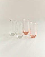 Four glass tumblers with pink bases on a light gray background
