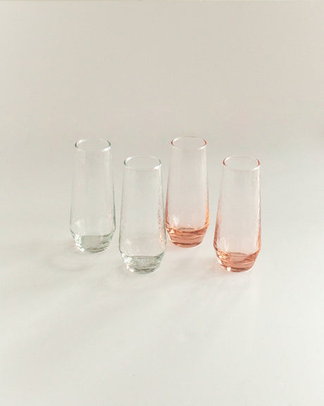 Four glass tumblers with pink bases on a light gray background