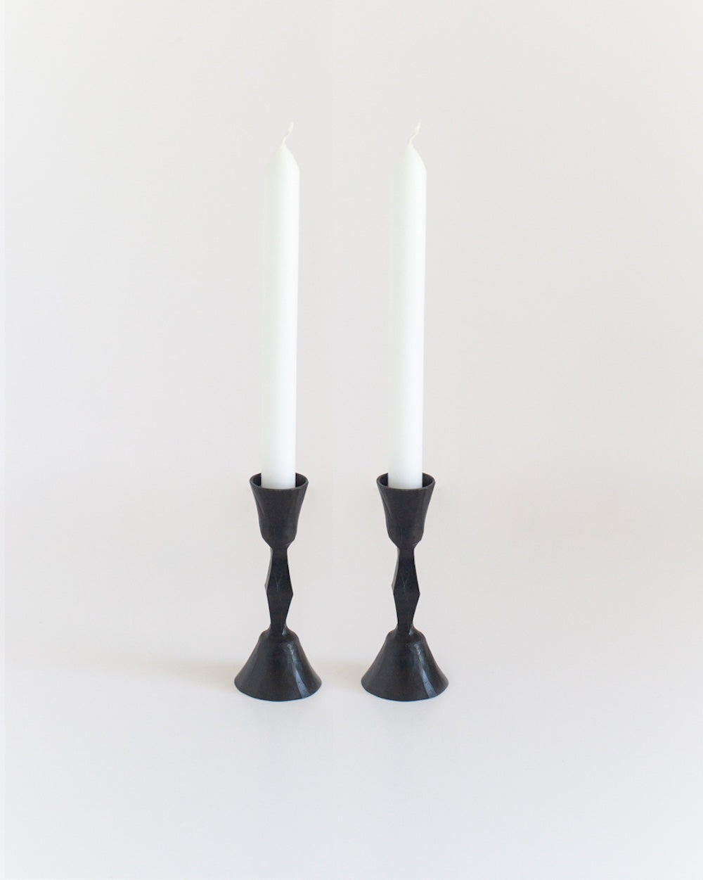 Black candle holders with white candles on a white background
