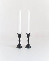 Black candle holders with white candles on a white background