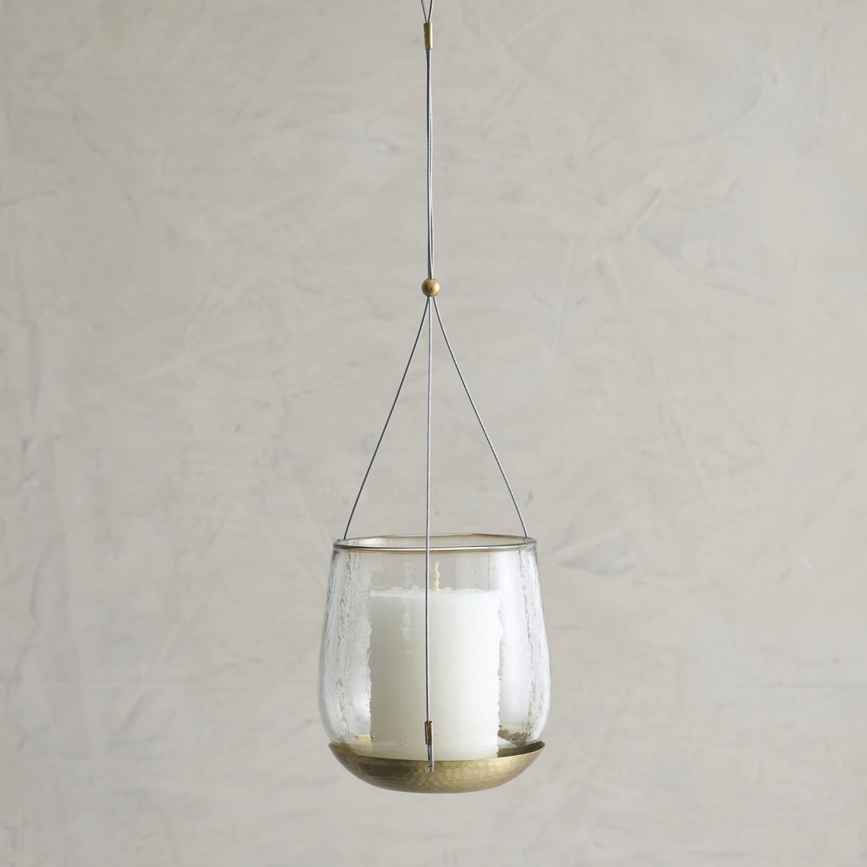 Hanging glass lantern with candle inside on a plain background