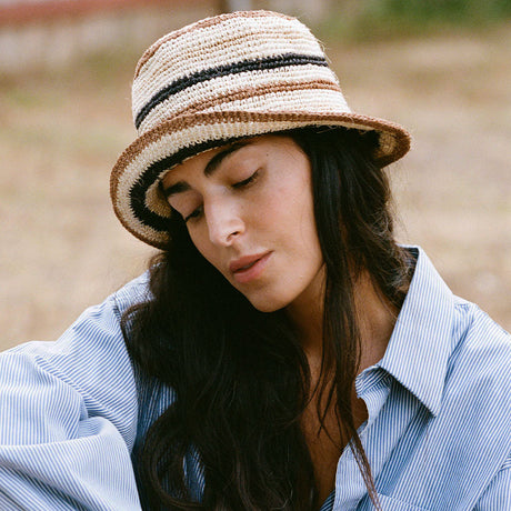 Woman wearing a striped straw hat and blue shirt outdoors