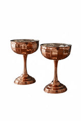 Two copper-colored cocktail glasses on a white background
