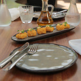 Dessert plate with small pastries on a wooden table with cutlery and water glasses.
