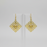 Gold earrings with intricate designs on a light gray background