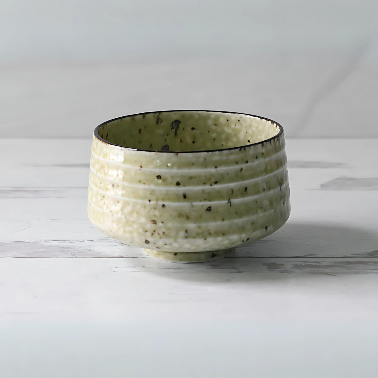 The Kaneni White Ceramic Matcha Bowl is a textured, green ceramic piece with a speckled pattern, reminiscent of traditional Japanese pottery. It perfectly complements any matcha accessory collection.