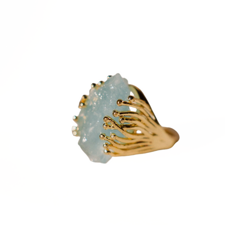 Ring with gold band and light blue stone on a white background