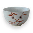 The Bamboo Matcha Bowl is a speckled white ceramic bowl featuring a painted floral design on a black background, showcasing the elegance of Minoyaki pottery, and is perfect for a traditional matcha tea ceremony.