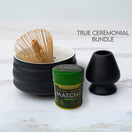 Ceremonial matcha tea set with a bamboo whisk, sleek matcha tin, and Black and White Ceramic Matcha Bowl on a white surface.