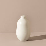 White vase on a beige surface with a pinkish-beige background