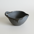 Black ceramic bowl with handle on a white background