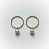 Gold hoop earrings with pearls on a light gray background