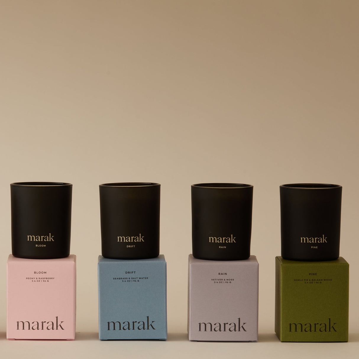 Four black candles on colorful boxes with 'marak' branding against a beige background. Collection Votive Set | 3.4oz Soy Wax Scented Candles