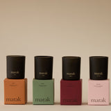 Four black candles on colorful boxes with 'marak' branding against a beige background. Collection Votive Set | 3.4oz Soy Wax Scented Candles