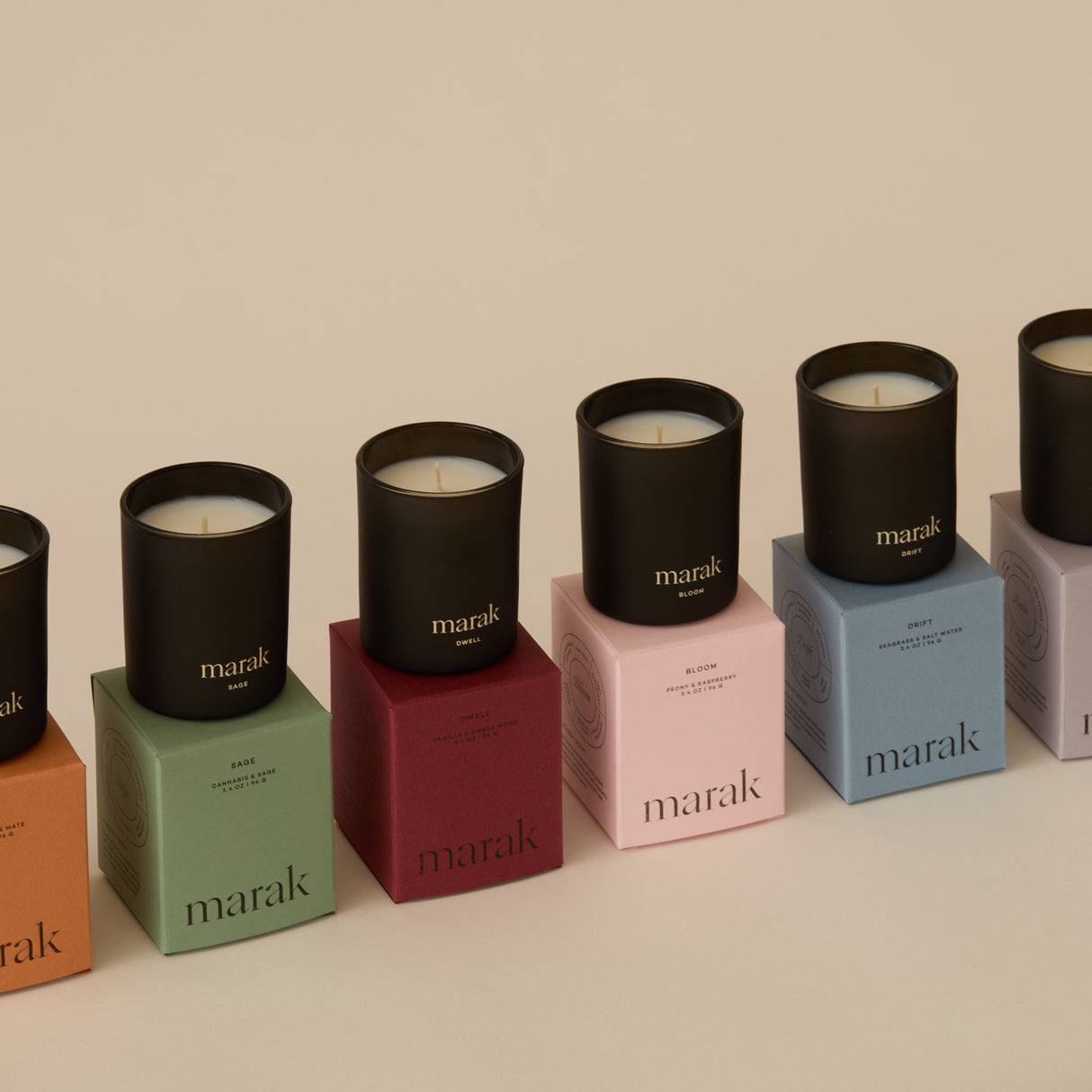 Row of black candles on colorful boxes with 'marak' branding on a beige background. Collection Votive Set | 3.4oz Soy Wax Scented Candles