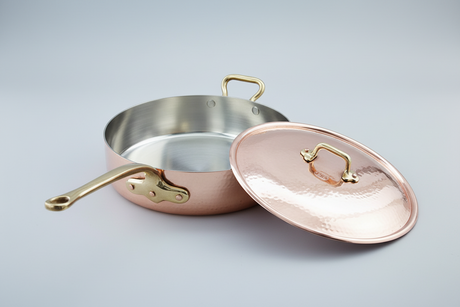 Copper cookware set with a pan and lid on a light gray background