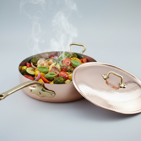 Copper pan with vegetables cooking, lid open on a light gray background