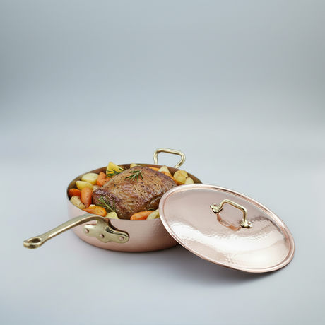 Copper pot with food inside on a light gray background