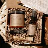 Set of natural skincare products including a bath soak, lip balm, and pillow mist in a decorative box.