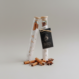 Two glass tubes with cinnamon sticks and star anise on a gray background
