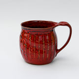 The Handmade Big Red Ceramic Tea or Coffee Mug from Japan features a textured surface and curved handle, showcasing exquisite Japanese craftsmanship against a plain white background.