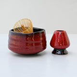 The Red Matcha Bowl and Bamboo Whisk from the Matcha Set are perfect with a small matching vase on a white surface, all beautifully crafted in Minoyaki pottery style.