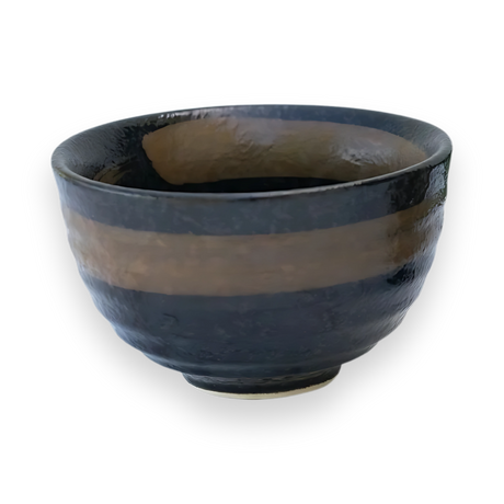The Dark Brown Glaze Ceramic Matcha Bowl is crafted from black ceramic using Minoyaki pottery techniques, featuring a glossy, uneven surface with a brown stripe around the middle on a black background.