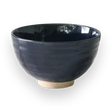 The Dark Navy Blue Ceramic Matcha Bowl, with its glossy finish and light-textured base, sits elegantly on a black background, making it perfect for any matcha tea starter set.