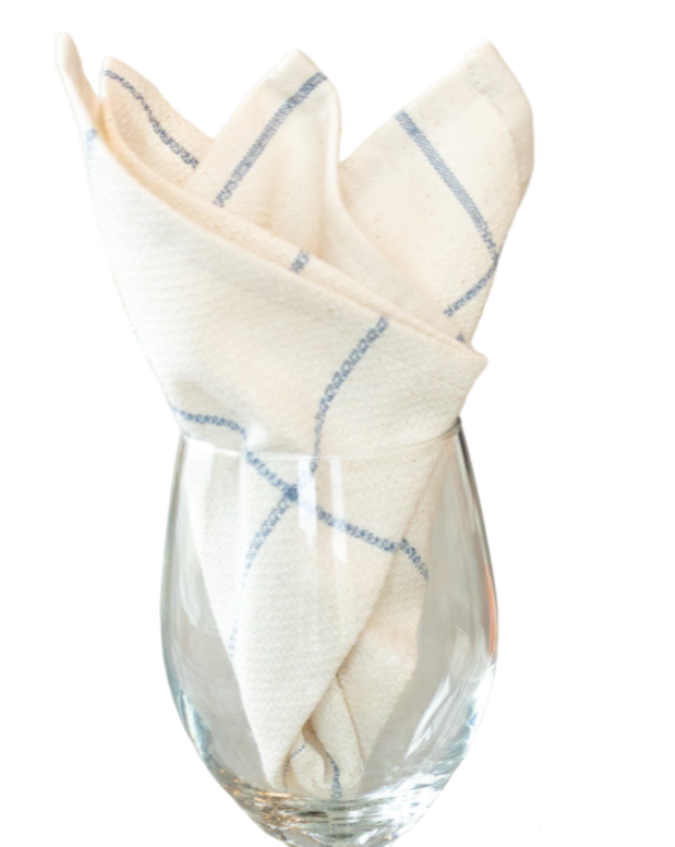 Clear glass with a folded white napkin featuring blue stripes on a white background