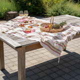 Picnic setup on a striped blanket with a basket of fruits and vegetables on a grassy field.