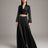 Woman wearing a black outfit with a long skirt and top on a plain background